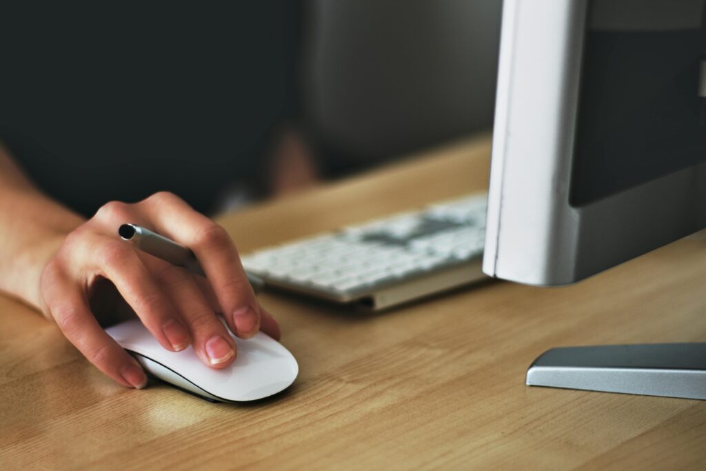 pexels-photo-392018-392018 A hand using a wireless mouse at a modern desk setup with a computer and keyboard.