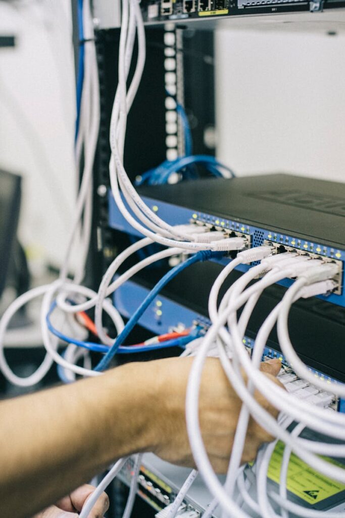 pexels-photo-442150-442150 An IT professional configuring network cables in a server rack, focusing on Ethernet connections.